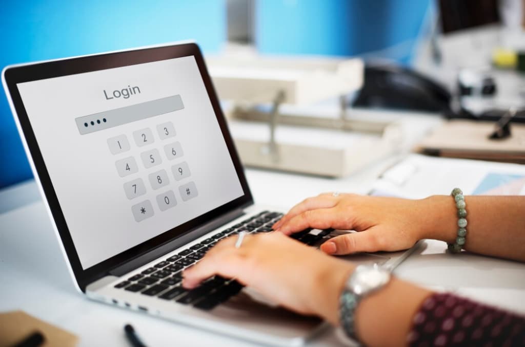 hands with accessories typing on the keyboard laptop with word login on it